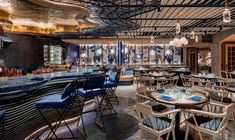 the inside of a restaurant with many tables and chairs, blue walls and ceiling lights