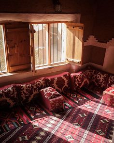 the sun shines through two windows onto a couch in a room with patterned carpet