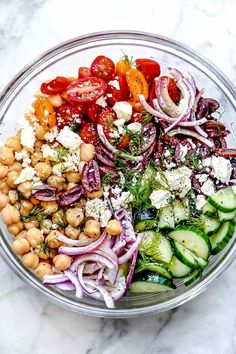 a glass bowl filled with vegetables and chickpeas