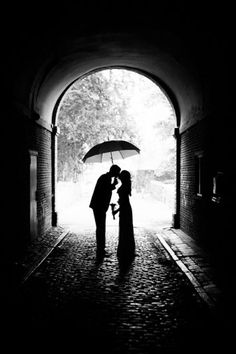 a couple kissing under an umbrella in the rain