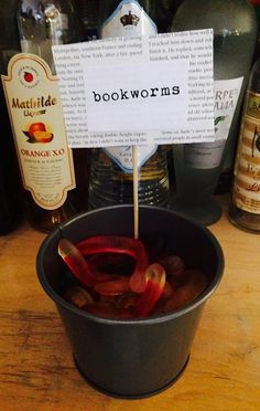 a bucket filled with red peppers sitting on top of a wooden table next to bottles