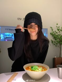 a woman eating soup with chopsticks in her mouth