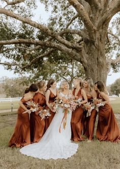 a group of women standing next to each other in front of a tree