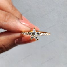 a woman's hand holding a gold ring with a star shaped diamond on it