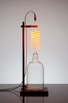 a light that is on top of a table next to a glass bottle with a wire in it