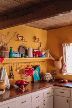 a kitchen with yellow walls and wooden shelves filled with pots, pans and other items