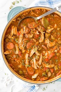 a large pot filled with soup on top of a white table cloth next to a spoon