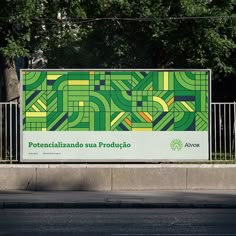 a large sign on the side of a road in front of a fence and trees