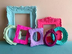 four different colored frames sitting next to each other on a blue counter top with pink and green trim