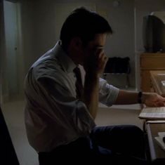 a man sitting in front of a laptop computer on top of a desk next to a keyboard