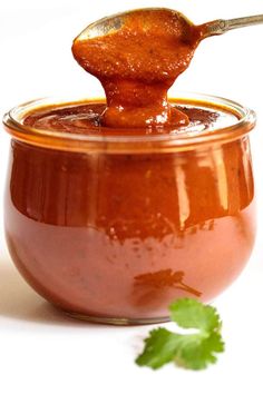 a spoon full of sauce sitting on top of a jar