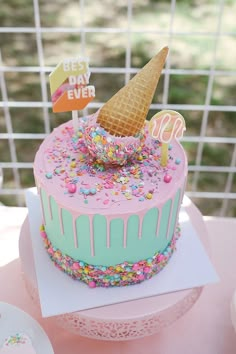 a birthday cake decorated with sprinkles and an ice cream cone on top