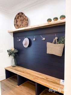 a wooden bench sitting in front of a wall with pots and plants on top of it