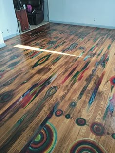 a wooden floor with colorful circles painted on it and a black chair in the background