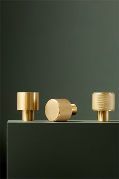 three brass knobs on a green surface