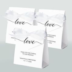 three white bags with the word love printed on them and ribbons tied around each bag