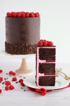 a chocolate cake with raspberry frosting on a plate next to a slice