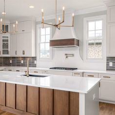 a large kitchen with white cabinets and wood flooring on the countertops, along with an island in the middle