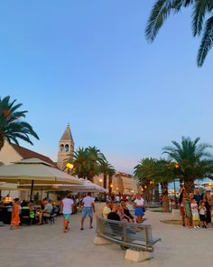 people are sitting at tables and eating under umbrellas on the beach in front of palm trees