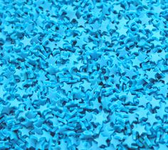 many blue stars are scattered together on the ground in this close up shot, with only one star visible