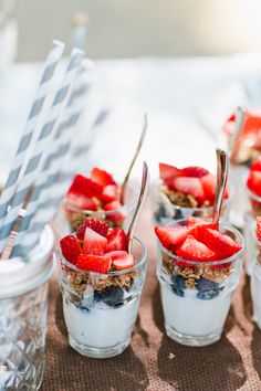 desserts with strawberries and yogurt are arranged in small glass cups on a table