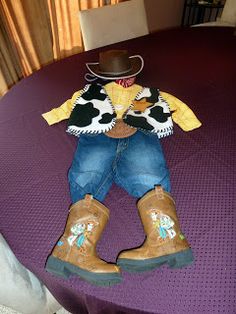 a child's cowboy outfit and boots sitting on top of a purple tablecloth