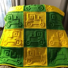 a green and yellow afghan sitting on top of a couch