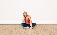 a woman sitting on the floor with her legs crossed in front of her face and smiling