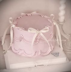 a pink cake sitting on top of a white box