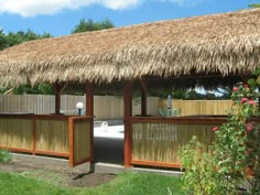 an outdoor hot tub in the middle of a yard with a thatched roof over it