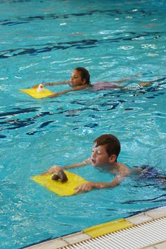 two children are playing in the pool with boogie boards