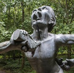 a statue in the shape of a man holding a can with his hands and mouth open