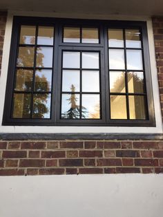 the reflection of trees in the windows of a brick building