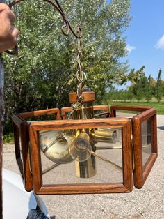 a person holding up a small wooden object with metal parts in it's center