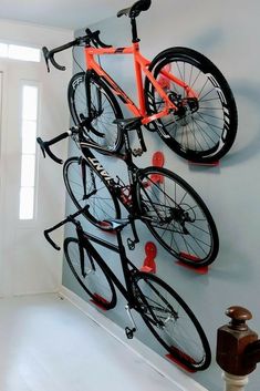 a bicycle mounted to the side of a wall next to a door with hooks on it