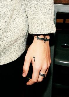 a person with a cross tattoo on their hand