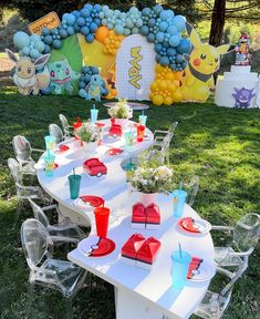 a table set up for a pokemon birthday party with balloons, plates and cups on it