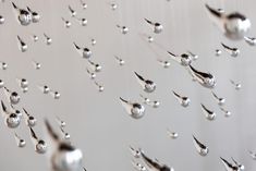 silver balls and spoons are hanging from the ceiling in front of a white wall