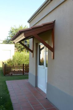 an outside view of a house with a white door and brown awning over it