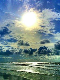 the sun shines brightly in the clouds above the ocean on a beach with waves