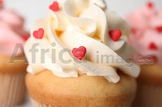 cupcakes with white frosting and red hearts on top