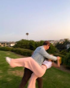 a man and woman are dancing in the grass outside with their arms around each other