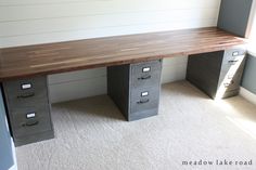 an office desk with three drawers and a shelf on the wall next to it in a room