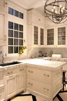 a kitchen with white cabinets and marble counter tops in the center, along with black and white checkered flooring