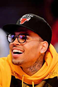 a close up of a person wearing glasses and a hat with tattoos on his arm