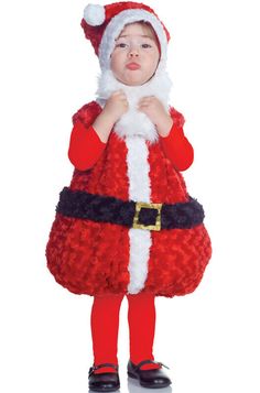 a little boy dressed as santa clause standing in front of a white background with his hand on his mouth