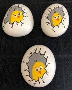 three yellow and gray birds painted on white rocks