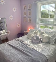 a white bed sitting under a window next to a dresser and mirror in a bedroom