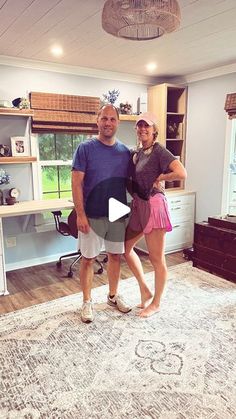 a man and woman standing in front of a rug on top of a wooden floor