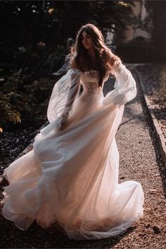 a woman in a white dress is walking down the road with her hands on her hips